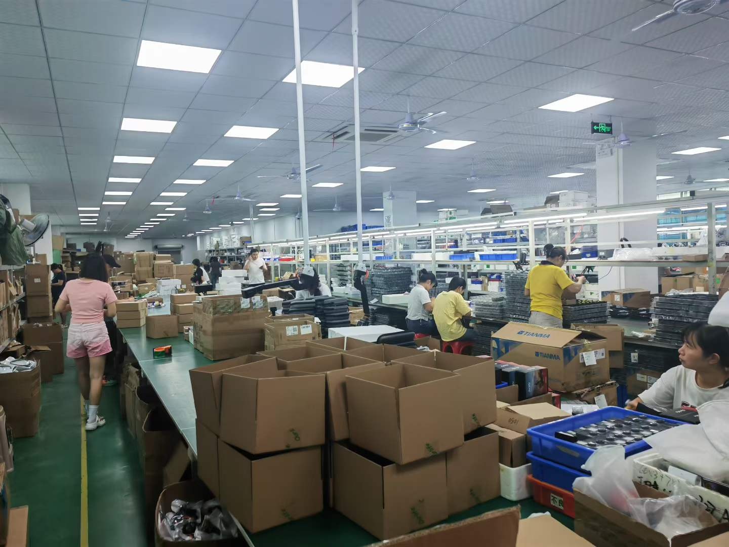 奥赛克包装车间实拍，纸箱、零售盒与操作工位分区摆放，呈现成品包装环节的现场布局。